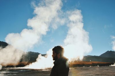 Man with arms raised against sky