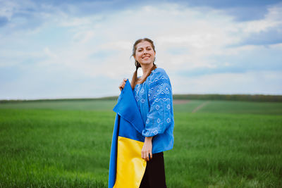 Young woman standing on field against sky