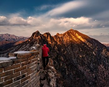 Rear view of woman standing on mountain against sky