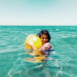 Portrait of woman with ball swimming in sea