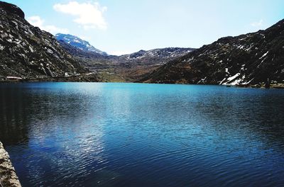 Scenic view of lake by mountains against sky