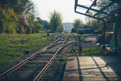 View of empty railroad station by tracks with trees 