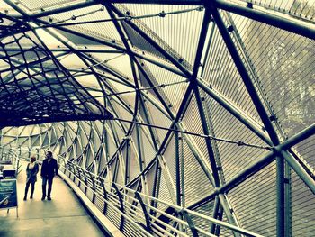 Rear view of people walking on metal structure