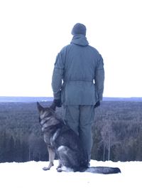 Rear view of man with dog against clear sky