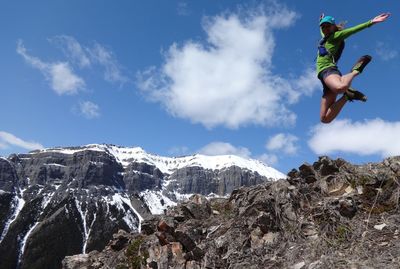 Happy woman in mid-air over mountains against sky