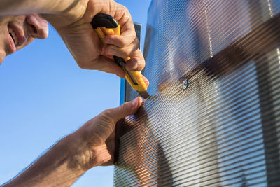 Low angle view of man working against clear blue sky