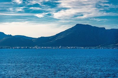 Scenic view of sea by mountains against sky