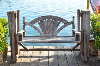 Empty chairs by swimming pool against lake