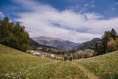 People on field by mountains against sky