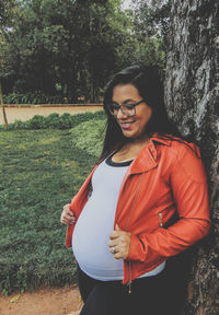 Portrait of smiling young woman standing by tree