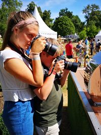 Midsection of woman holding camera while standing outdoors