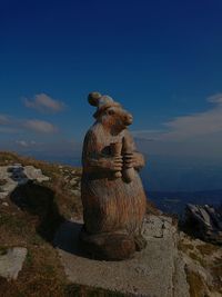 Statue on rock by sea against blue sky