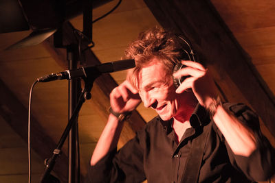 Close-up of man wearing headphones standing by microphone