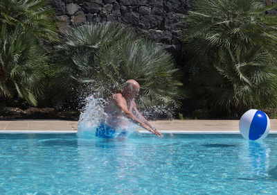 Senior man playing with ball in swimming pool