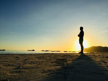 Silhouette mid adult man standing at beach against sky during sunset