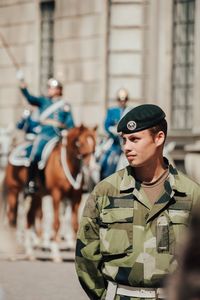 Soldier looking away while standing in city