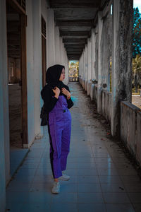 Full length of woman walking on footpath amidst building