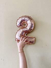 Midsection of person holding ice cream against wall