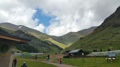 People on field by mountains against sky