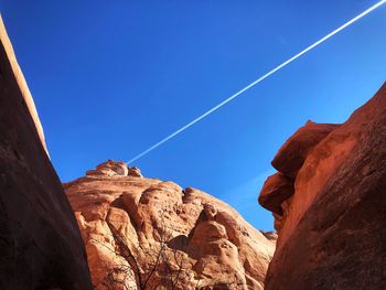 Low angle view of rock formation against clear blue sky