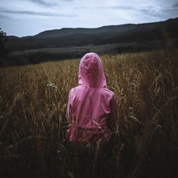 Rear view of woman with pink umbrella on field