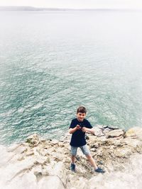 Boy standing on beach against sky