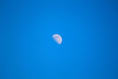 Low angle view of moon against clear blue sky