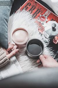 High angle view of woman holding coffee cup on table