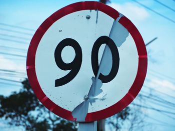 Close-up of road sign against sky
