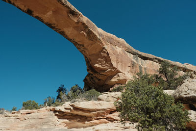 Low angle view of rock formation against clear blue sky