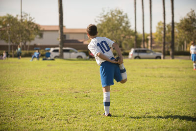 Young player in soccer uniform streching in the park