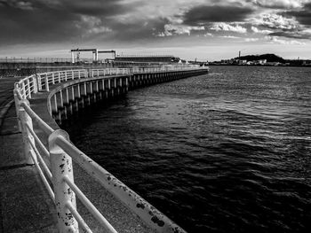 Pier on sea against cloudy sky