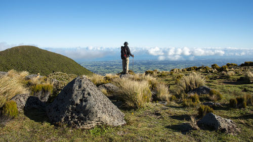 Man standing on rock against sky