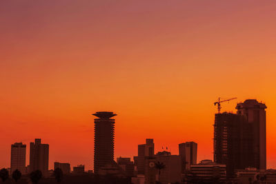Buildings in city against romantic sky at sunset