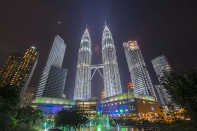 Low angle view of illuminated petronas towers against sky at night