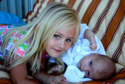 Portrait of siblings lying on sofa at home