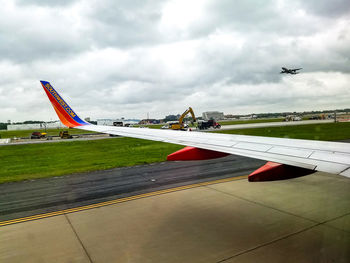 Airplane flying over airport runway against sky