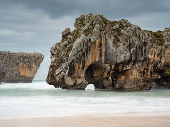 Scenic view of rock formation in sea against sky