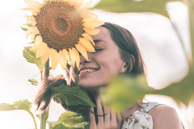 Close-up portrait of young woman with sunflower