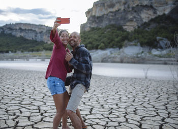 Couple taking a selfie at the edge of a lake during a trip.