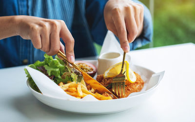 Closeup image of a woman eating fish and chips on table in the restaurant