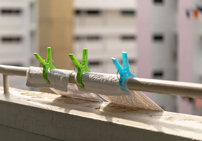 Close-up of clothespins on railing against wall
