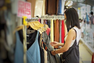 Side view of woman shopping the clothes  in store