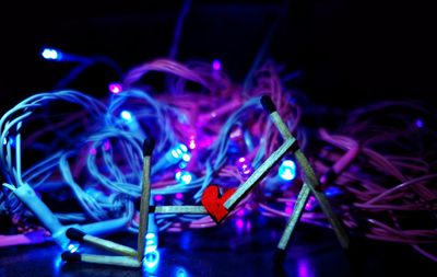 Close-up of matchsticks decorations against illuminated string lights at night