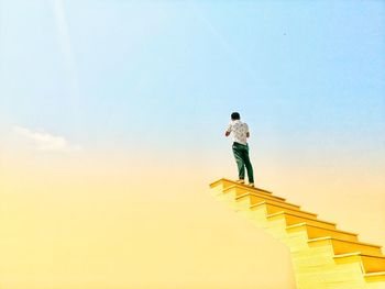 Low angle view of person standing on staircase against sky