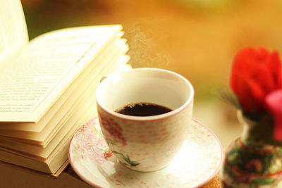 Close-up of coffee by novel on table