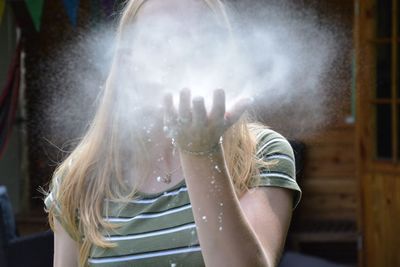 Teenage girl blowing powder against house