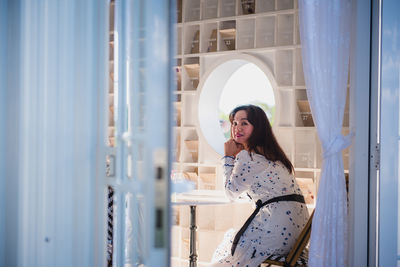 Side view of young woman looking through window