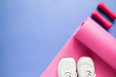 High angle view of exercise mat and shoes on purple background
