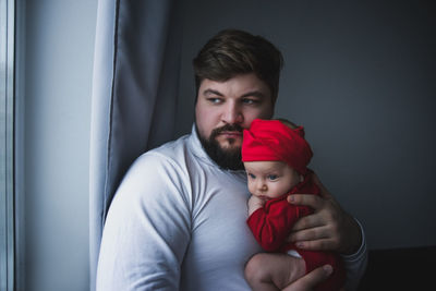 Father carrying daughter while standing at home